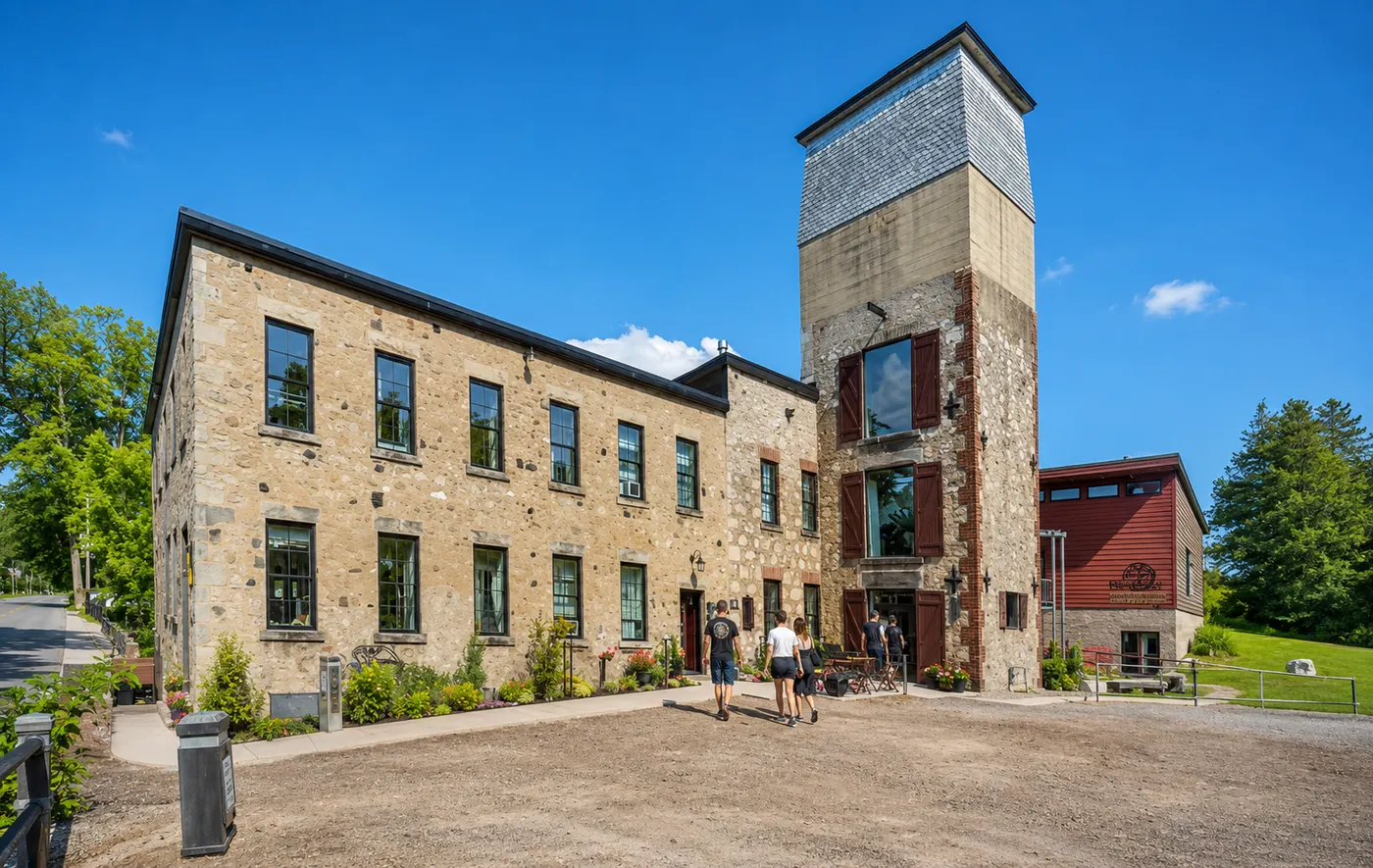 The restored 1880s stone mill at Alton Mill Arts Centre, with its shuttered tower and visitors walking toward the entrance.