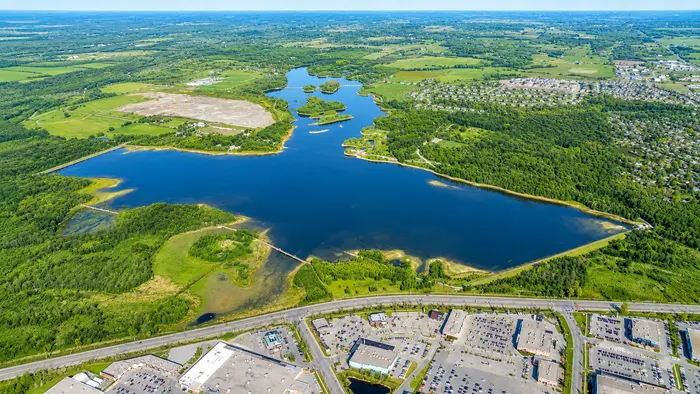 Aerial view of Island Lake Conservation Area, showing the reservoir, its causeways and boardwalks, the surrounding forest, and the edge of Orangeville along Highway 10.
