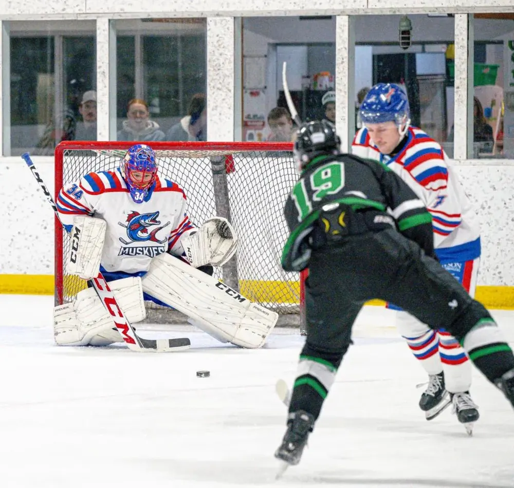 The Muskies goaltender squaring up to an incoming shot as an opposing forward winds up in the slot.