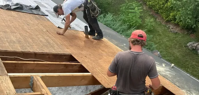 Two Renovations By Shane crew laying roof sheathing across open rafters on a full roof build.